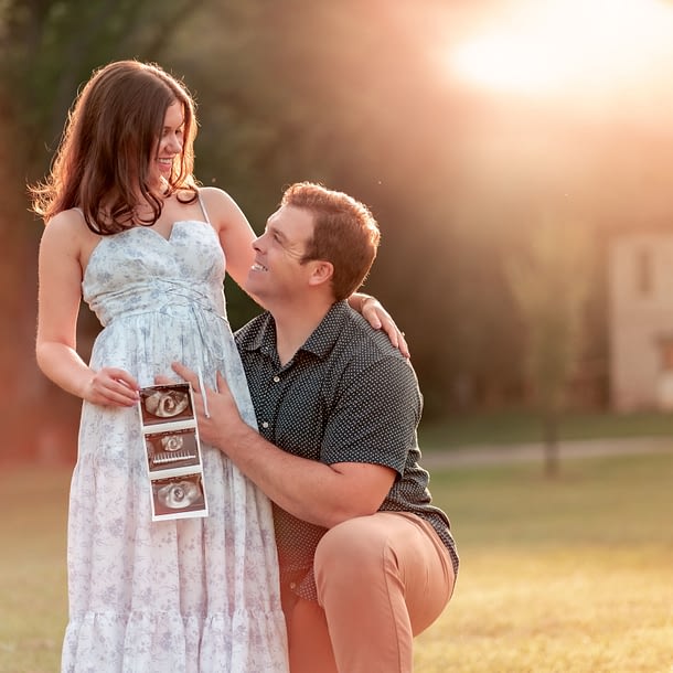 Couple smiling while holding a sonogram photo at Morven Park in Leesburg, Virginia.