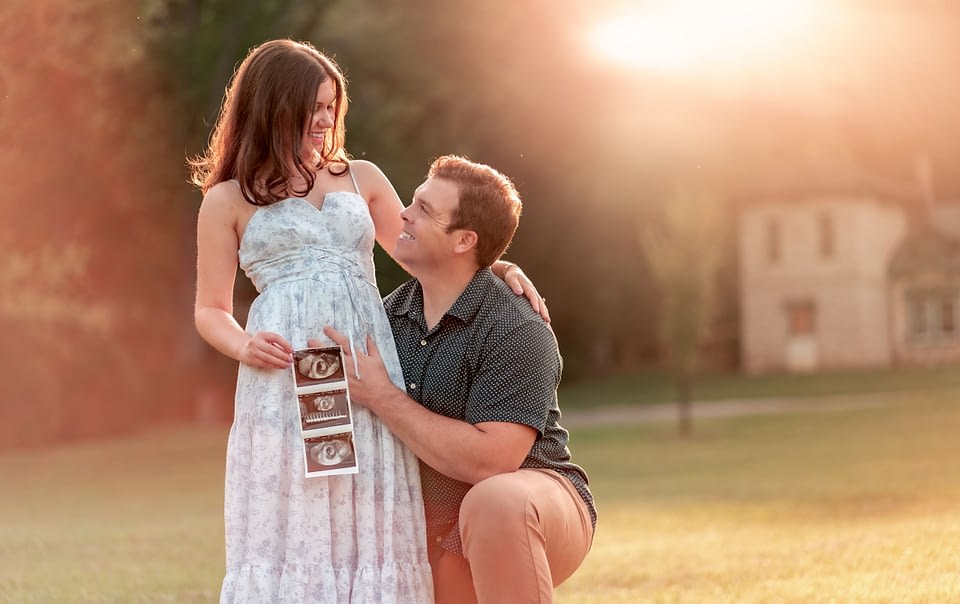 Couple smiling while holding a sonogram photo at Morven Park in Leesburg, Virginia.