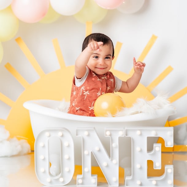 A summer themed cake smash portrait of a baby boy in a small bath tub.