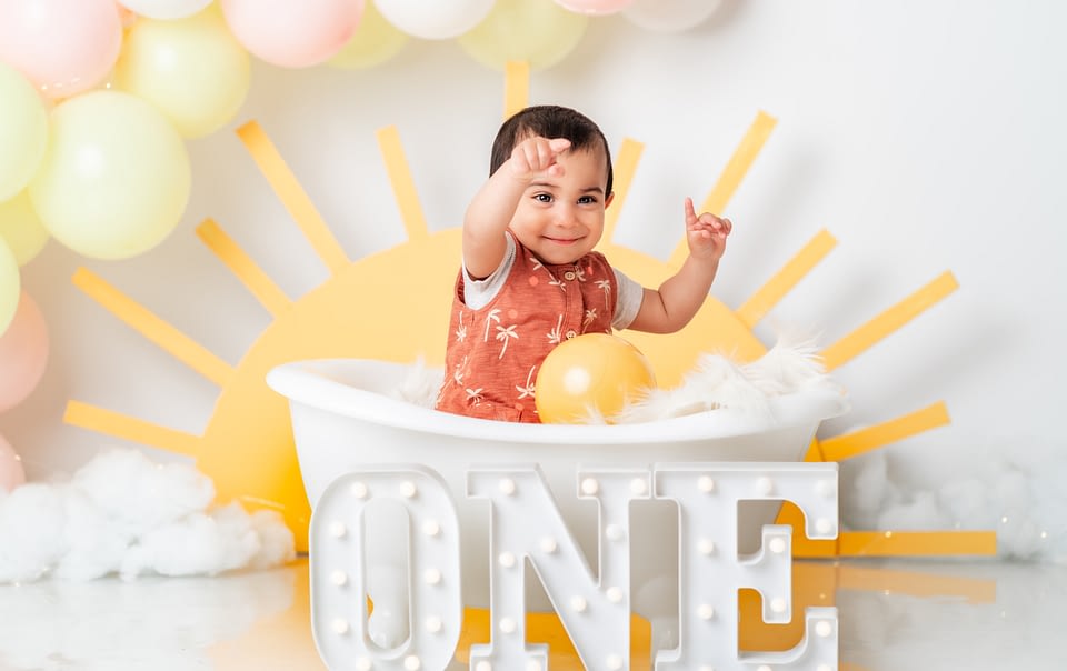 A summer themed cake smash portrait of a baby boy in a small bath tub.